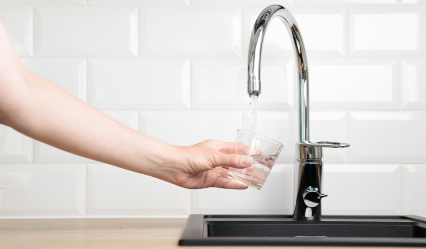 Pour tap water from the kitchen faucet into a glass